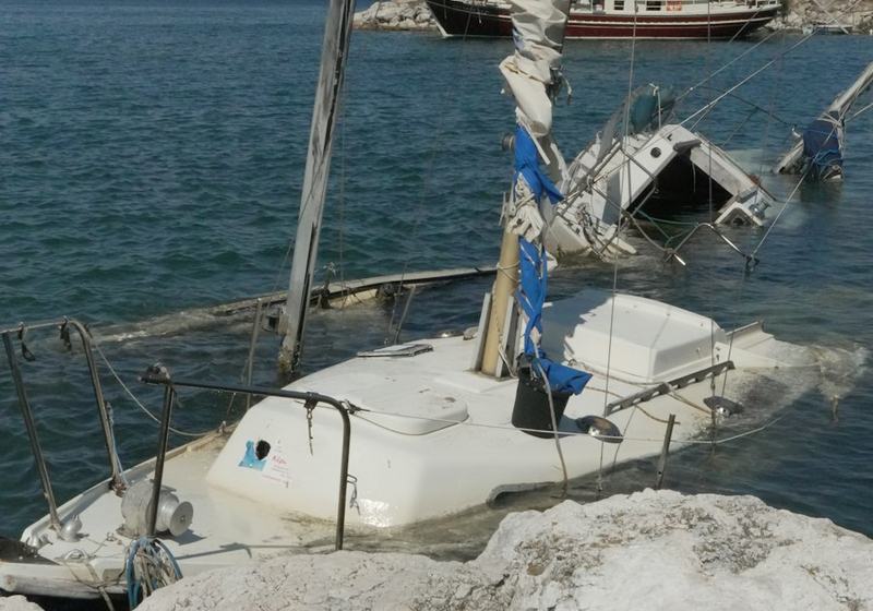 Sailboat partly sunk beside a rocky shore